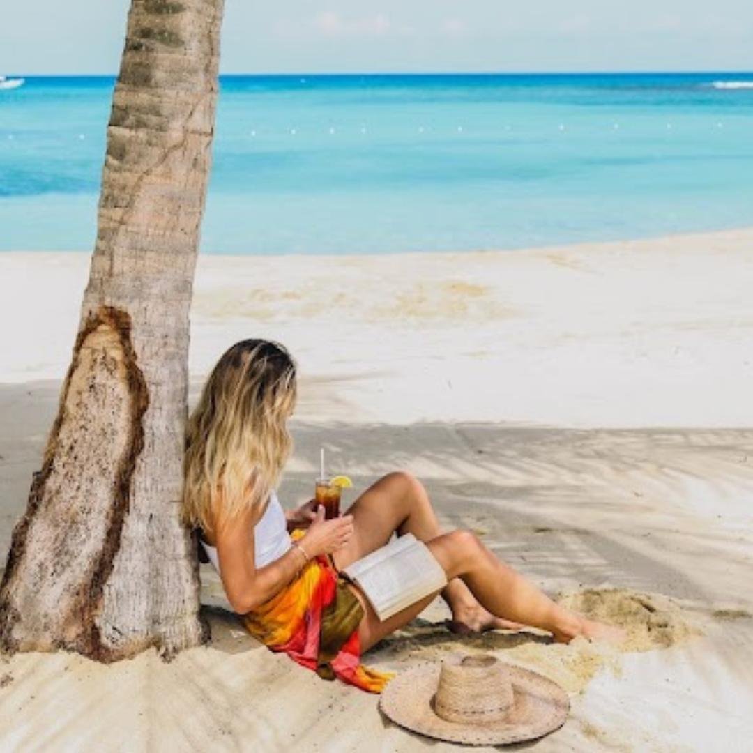 Woman sitting under a palm tree on the beach in Jamaica